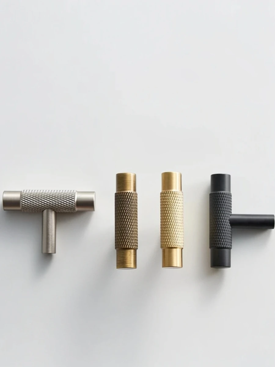 A minimalist product display of four Nurlin knurled metal cabinet handles in different finishes brushed nickel, antique brass, satin gold, and matte black. The collection includes two T-bar styles and two cylindrical knobs, all featuring a textured diamond-pattern grip against a clean white background.