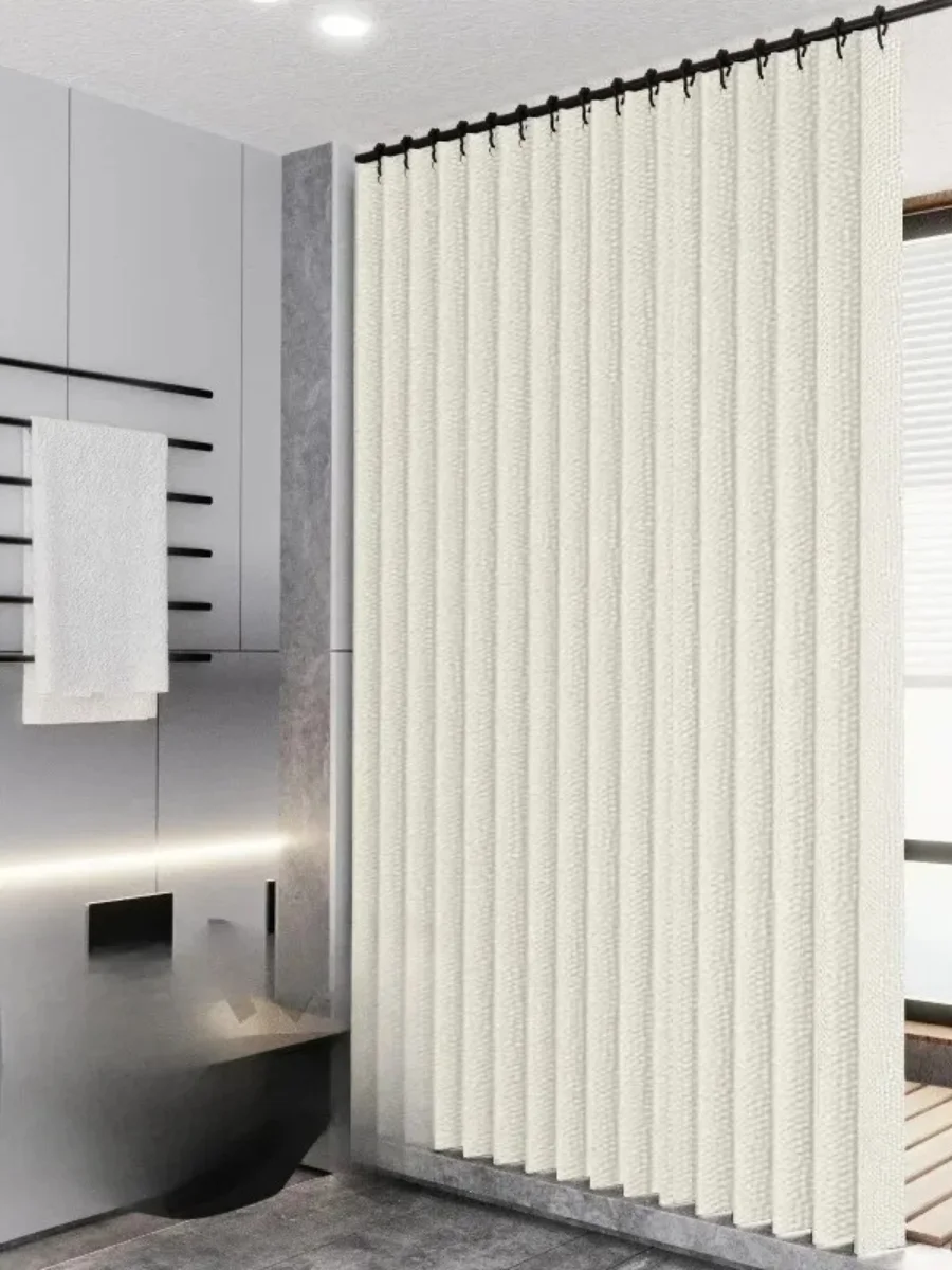 Modern minimalist off-white folding linen shower curtain with a crisp pleated accordion design, hanging from sleek black rings in a high-end gray stone bathroom.