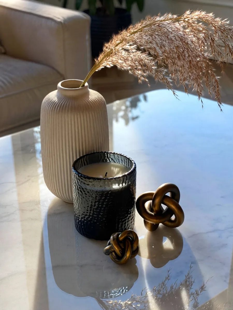 Close-up of three decorative objects on a marble table following affordable luxury interior design rules for styling.