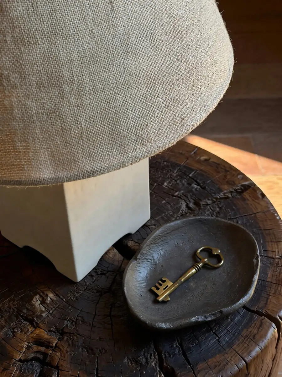 Close-up of a modern lamp on a vintage wood table following affordable luxury interior design rules.