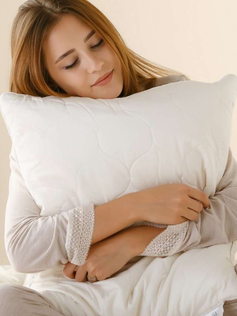 An elegant quilted white bed pillow sitting upright, showcasing its dense, supportive loft and cotton sateen construction.