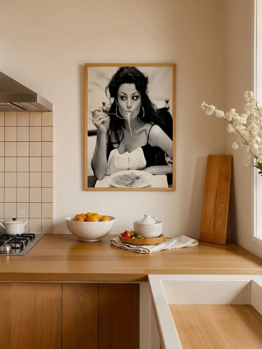  High-Fashion Italian Dining (Sophia Eating Spaghetti) black and white photography print framed elegantly in a dark wood border hanging above an intimate dining table setting.