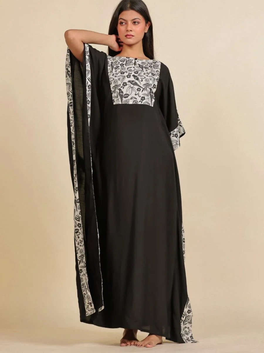 A full-length black modal kaftan gown featuring a contrasting rectangular white yoke with black botanical bird prints.
