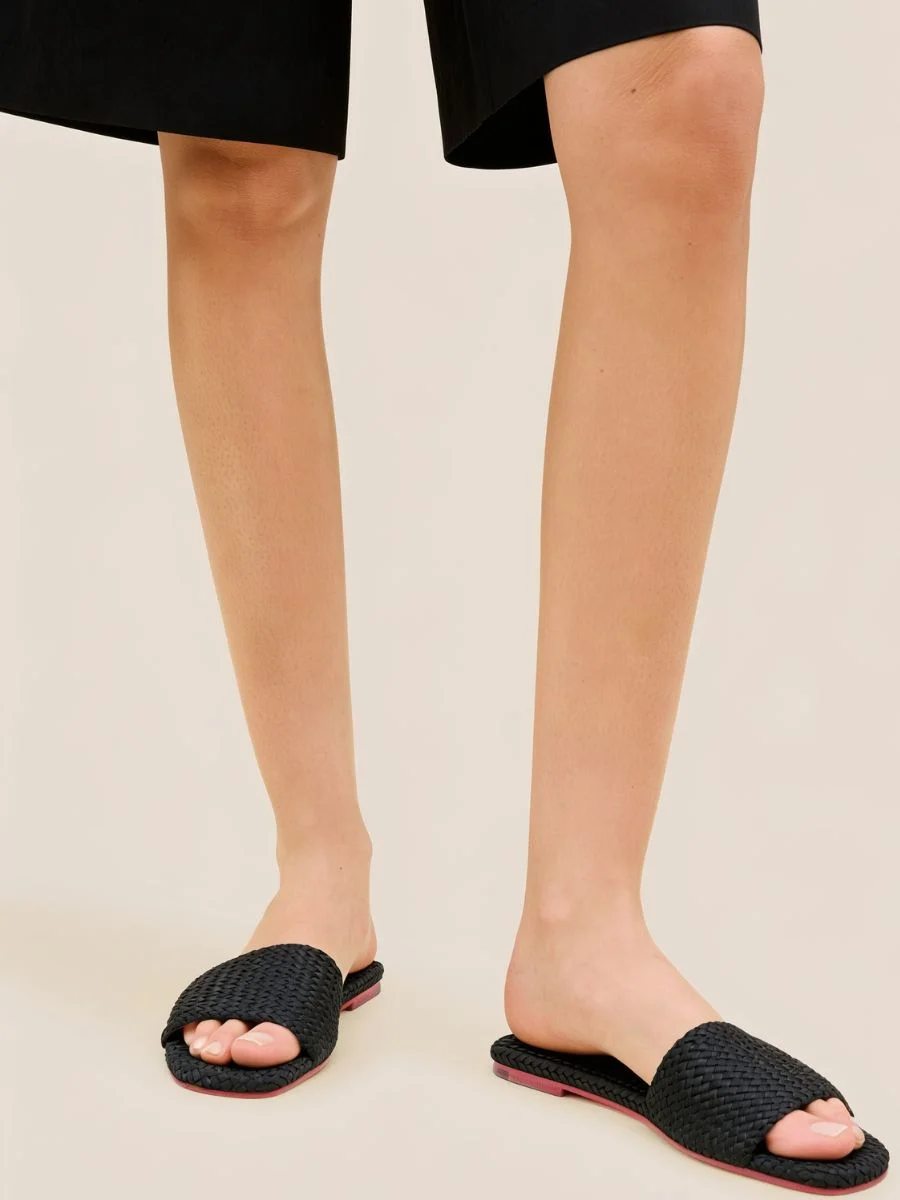 A woman wearing the Cartolina Nantucket St. Barths Slide in Onyx featuring a wide black handwoven neoprene front strap and a clean square-toe base.