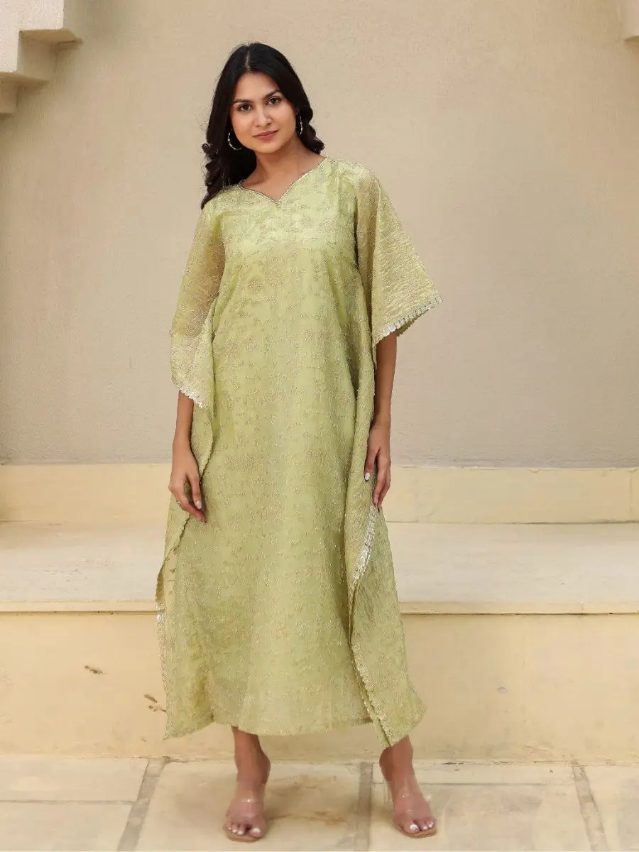 A woman modeling a lime green embroidered viscose silk maxi kaftan dress with silver sequin trim and wide sleeves.