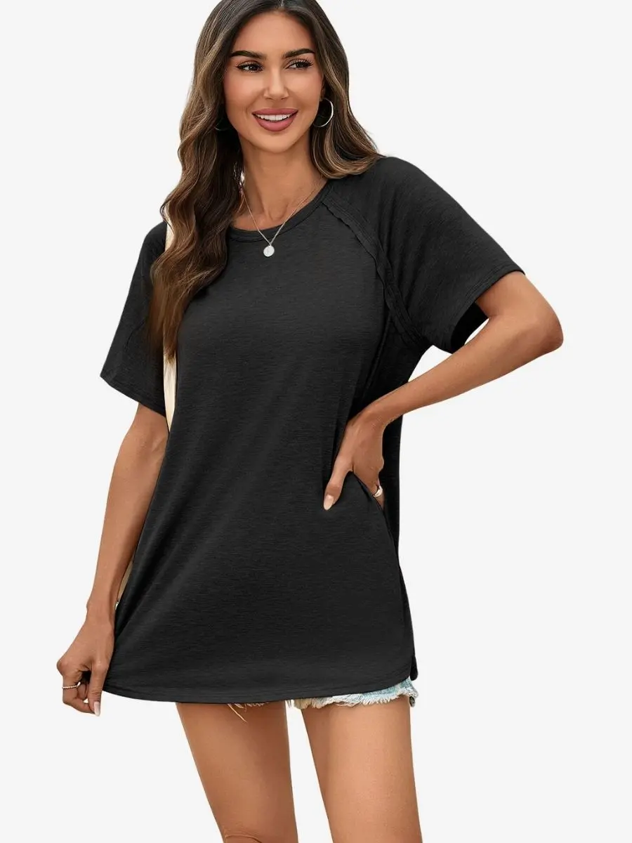 Front view of a woman wearing a black longline dolman sleeve t-shirt with high side slits.