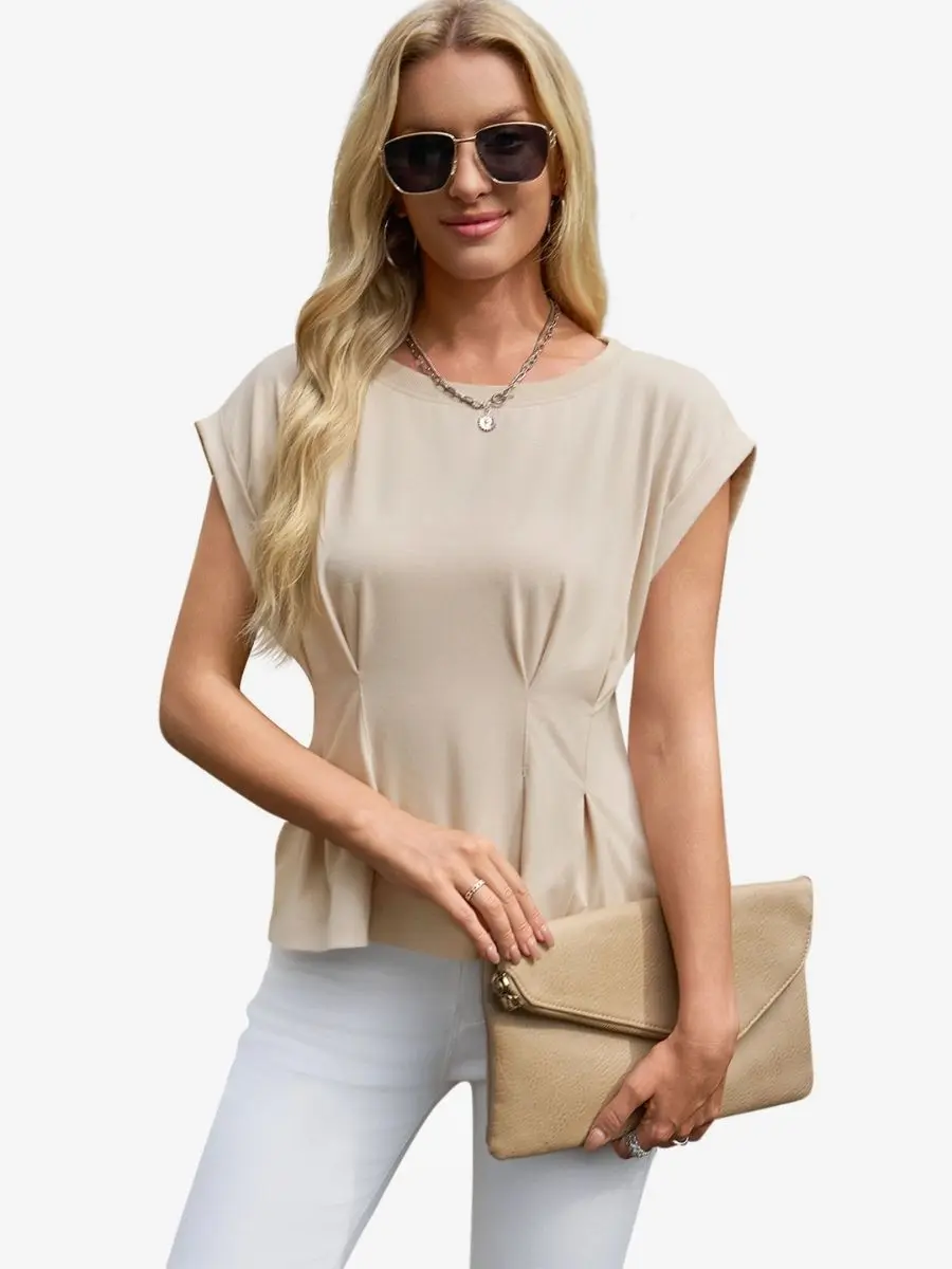 Front view of a woman wearing a light khaki pleated cap sleeve t-shirt with vertical waist pleats and white trousers.