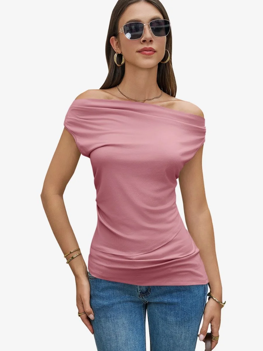 Front view of a woman wearing a pink asymmetric draped knit t-shirt with blue denim jeans and dark sunglasses.