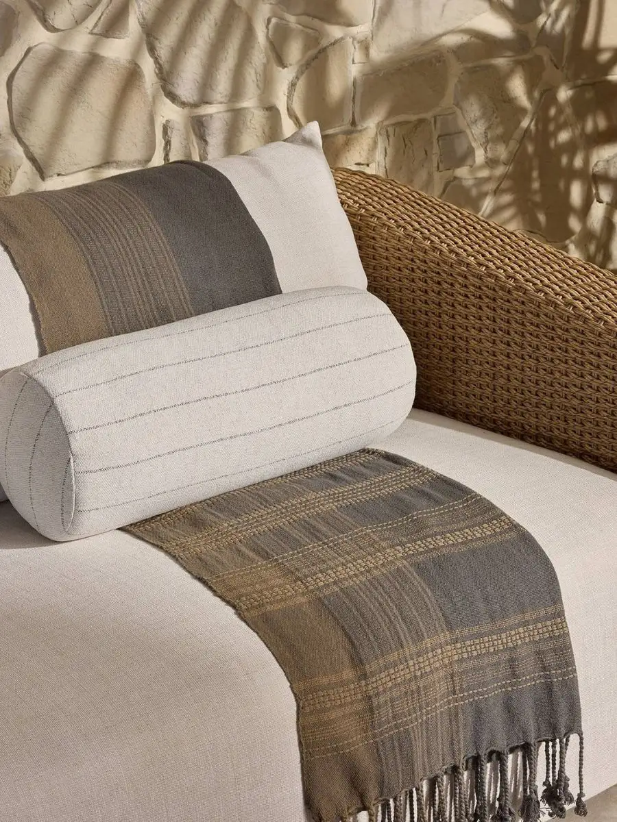 Old Money Home Decor: Easy Styling Steps to Make an Average Room Look High-End Striped Italian linen bolster pillow styled with a fringed earth tone throw blanket on outdoor lounge furniture. Textured neutrals for a quiet luxury patio aesthetic.