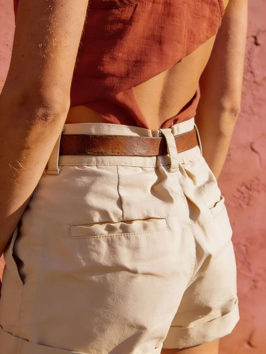 Close up vertical view of model showing chaotic fabric bunching and horizontal creases along the spine under a tight brown leather belt.