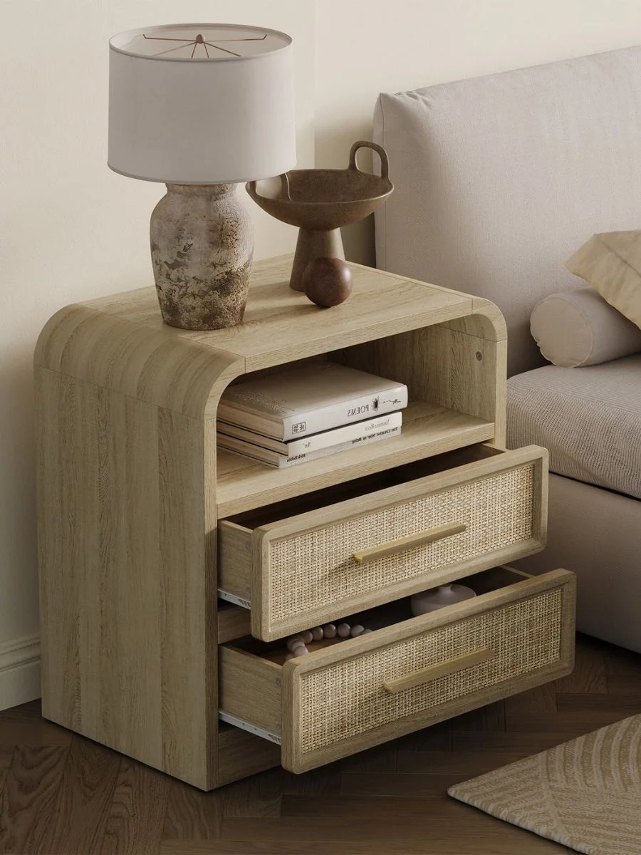 A close-up shot of a light oak bedside table with woven cane drawer fronts and a sleek polished gold handle.