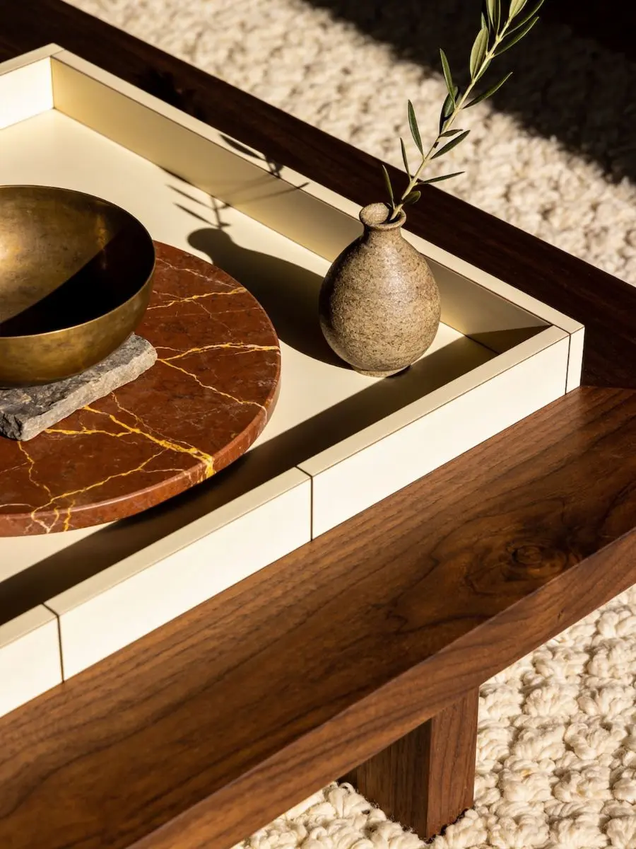 Old Money Home Decor: Easy Styling Steps to Make an Average Room Look High-End A close-up view of old money home decor styling on a walnut table with a large cream tray, a veined marble plate, and an olive branch vase.