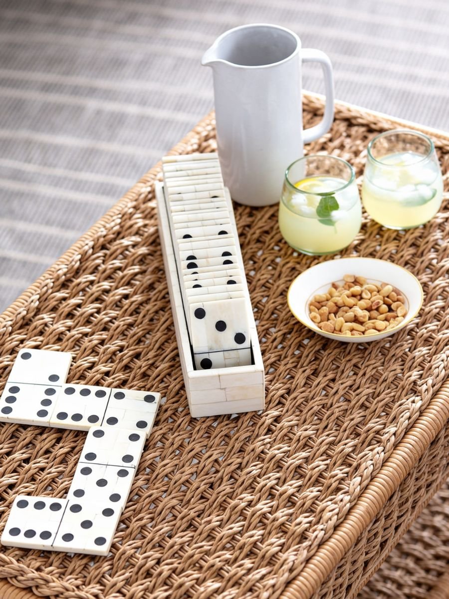 Old Money Home Decor: Easy Styling Steps to Make an Average Room Look High-End Regina Andrew Royal Dominos Set with a hand-inlaid bone tile case displayed on a woven seagrass coffee table. Timeless game night inspiration for old money aesthetics.