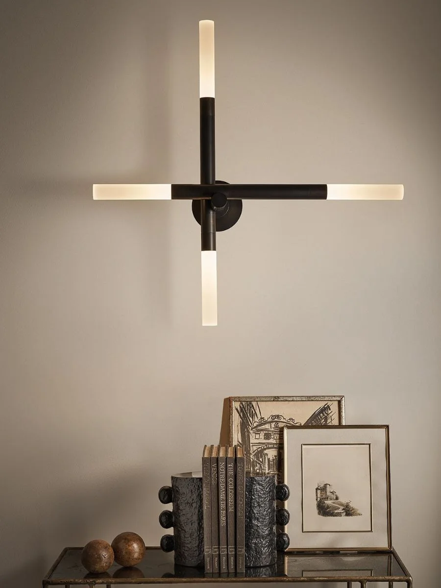 Old Money Home Decor: Easy Styling Steps to Make an Average Room Look High-End Black structural bookends and vintage art frames styled on a metal console table under a minimalist geometric wall light. High-end hallway console table styling with an old money vibe.