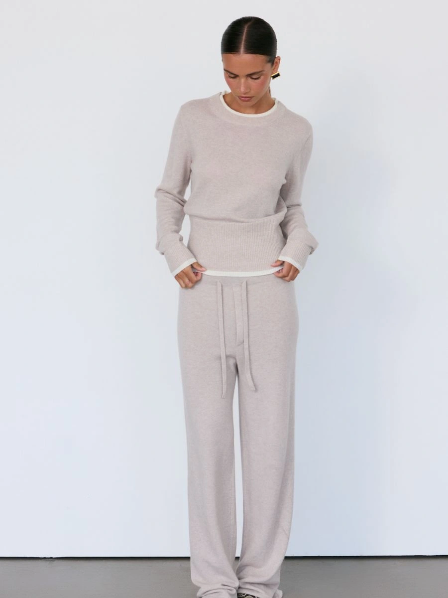 Model wearing a light beige Artless Tove wool-cashmere crewneck sweater and matching straight-leg lounge trouser.