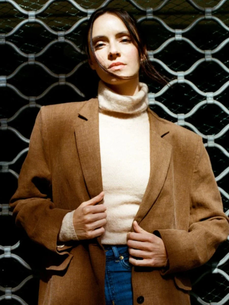 Close-up of a woman wearing the brown Má + Lin Maeve linen and wool blend blazer over a cream turtleneck.