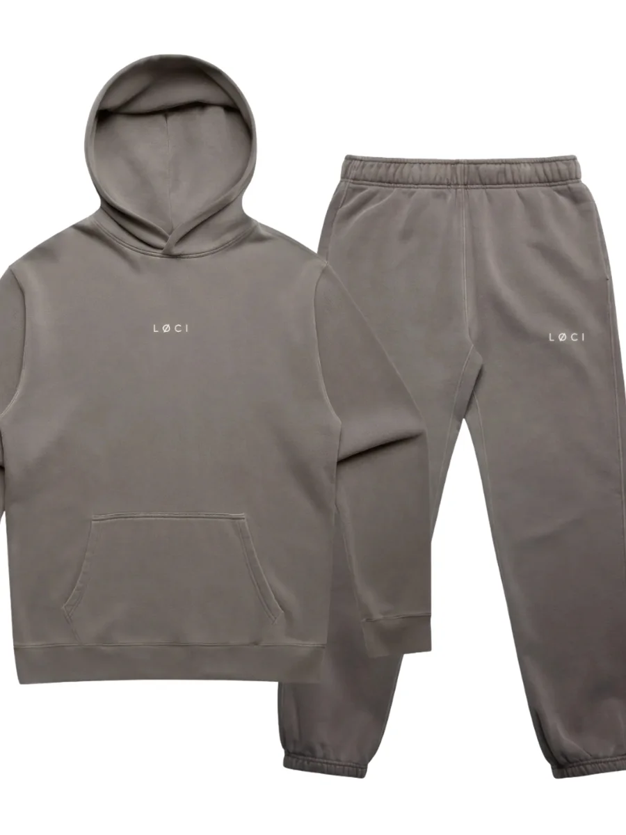 A matching vintage grey tracksuit set featuring a pullover hoodie with a front pocket beside elastic-waist joggers, both displaying a minimal white central logo.