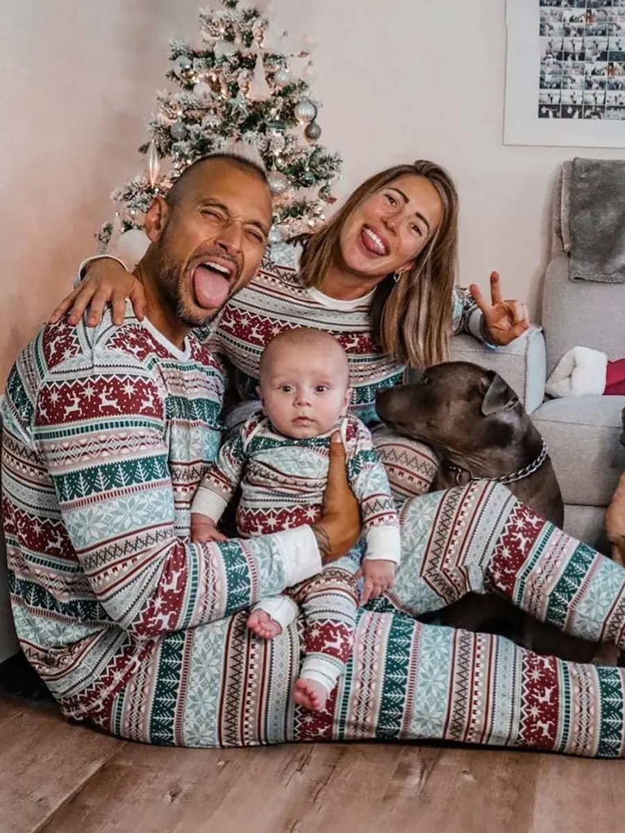 A cheerful family and their dog modeling a matching family holiday pajama set pattern in front of a Christmas tree.

