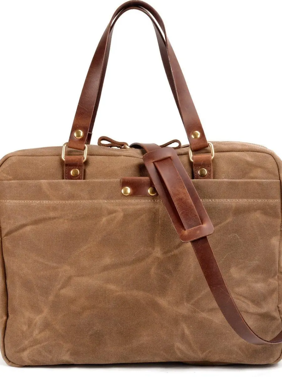 Brown waxed canvas briefcase laptop bag with dark brown leather top handles and a matching detachable leather shoulder strap on a white background.