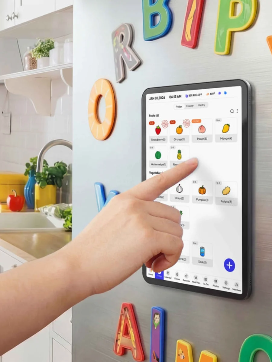 Person using a hand to touch a black bezel digital fridge calendar touchscreen displaying food inventory attached magnetically to a stainless steel refrigerator door with colorful letters.