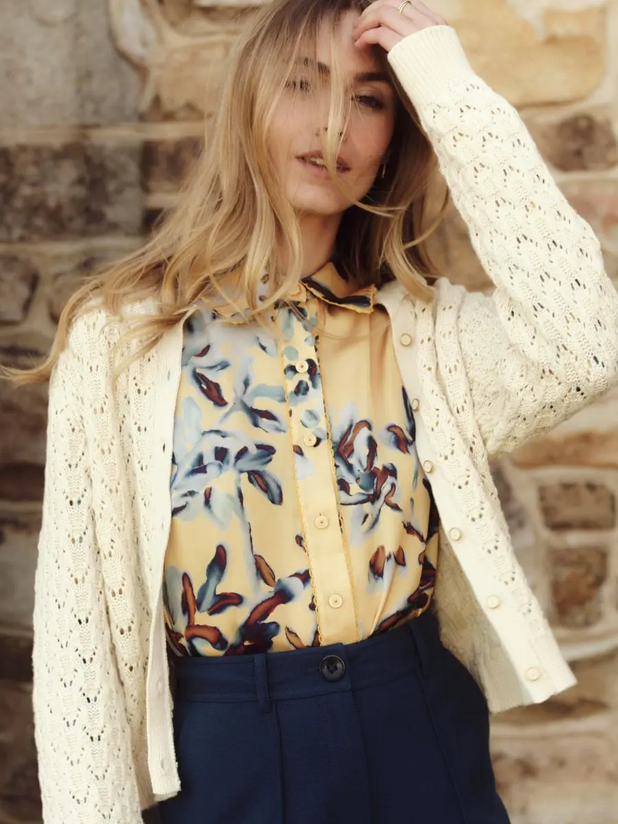A model wearing an ivory Cartolina Nantucket cotton-cashmere cardigan sweater with pointelle stitching featured in the classy capsule wardrobe checklist for styling elegant outfits for women.