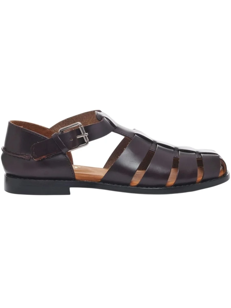 A side profile view of a dark brown leather Gurkha sandal from Sebago featuring an interlocking woven cage strap design, a closed toe, a secure ankle strap buckle, and a low flat leather sole against a plain white background.